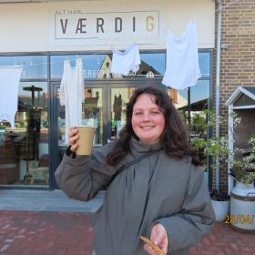 Pige foran butik værdig, med en kop kaffe.